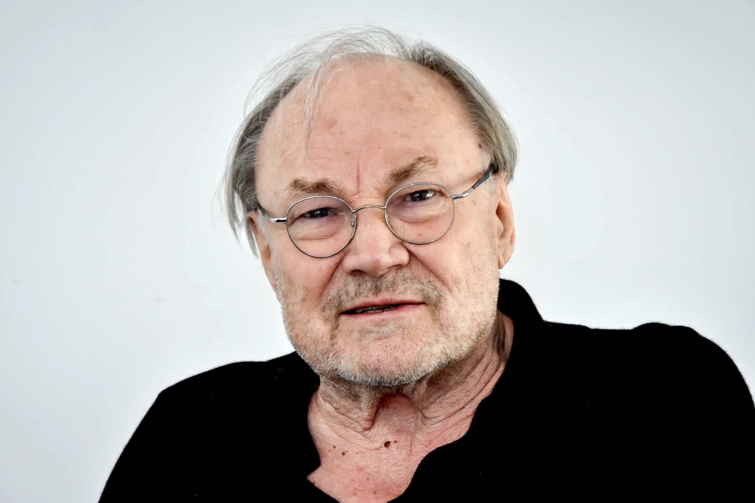 Klaus Maria Brandauer mit ernstem Blick, frontal aufgenommen, trägt Brille und schwarzen Pullover.