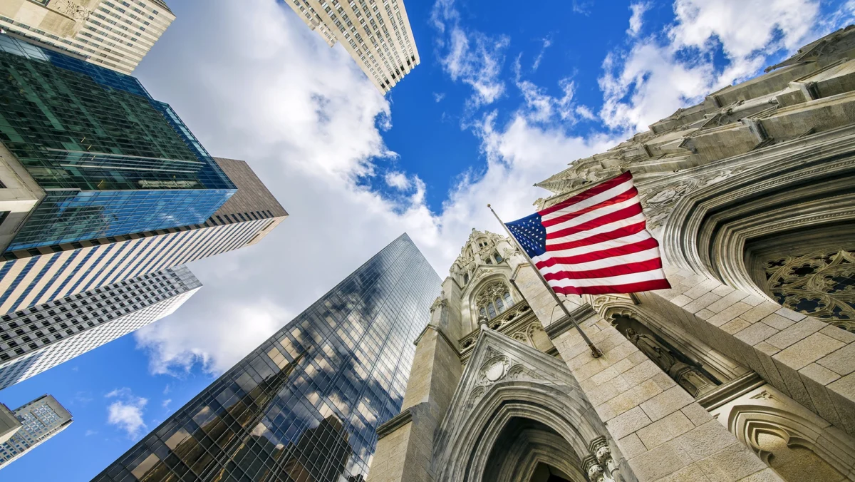 US-Flagge vor Kirche und modernen Hochhäusern in New York City